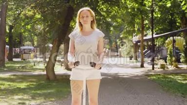 穿白色短裤的女孩，在<strong>晴朗</strong>的晴天骑着赛格威。 夏天公园和<strong>阳光</strong>。 4k，慢镜头拍摄